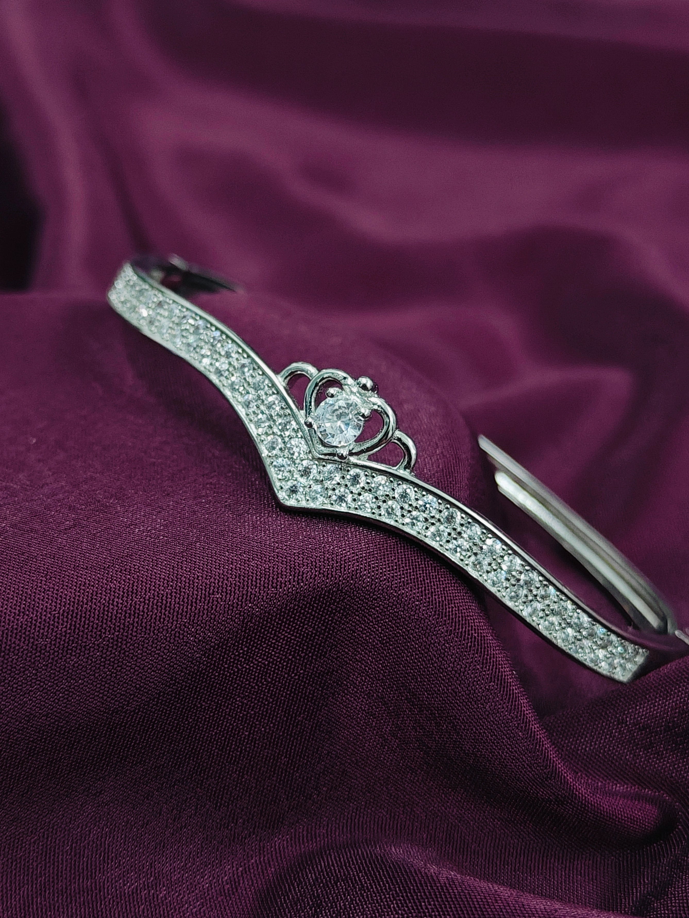 Silver tiara with a central gemstone on a purple fabric background